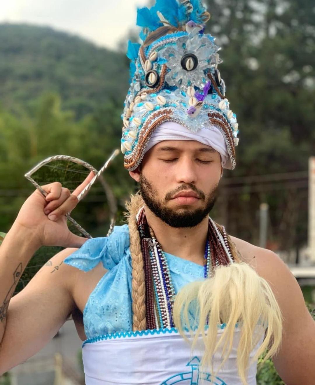 Orixá com adê azul e contas sagradas em festa pública